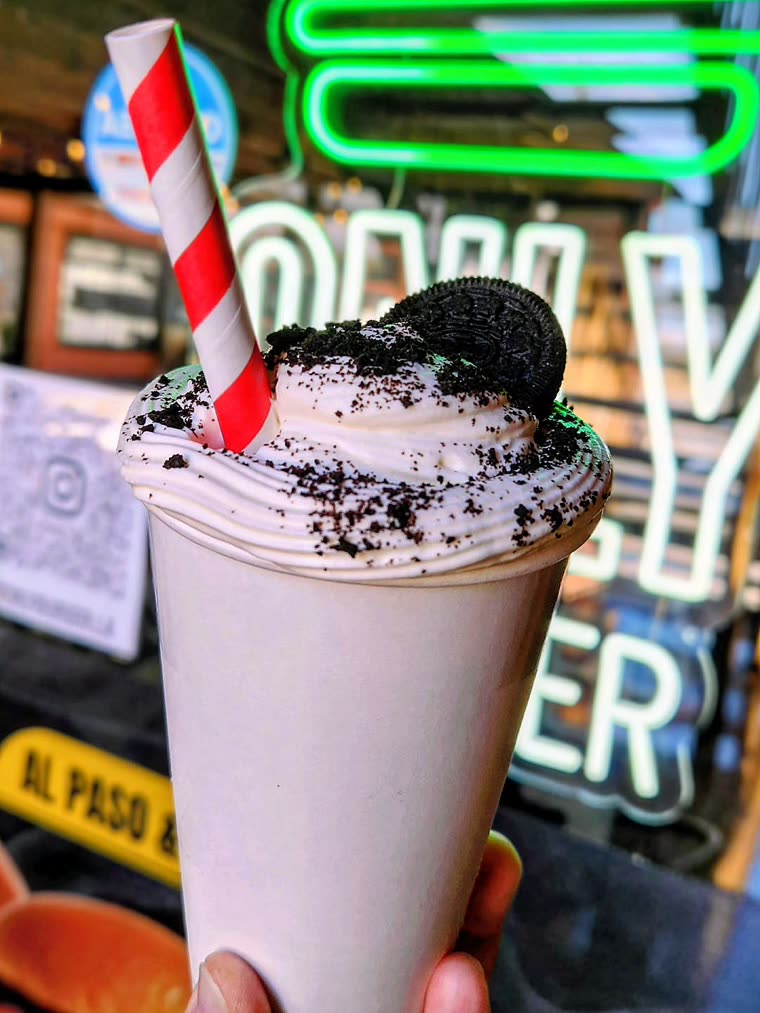 Shake de oreo frente al letrero de neón verde del local